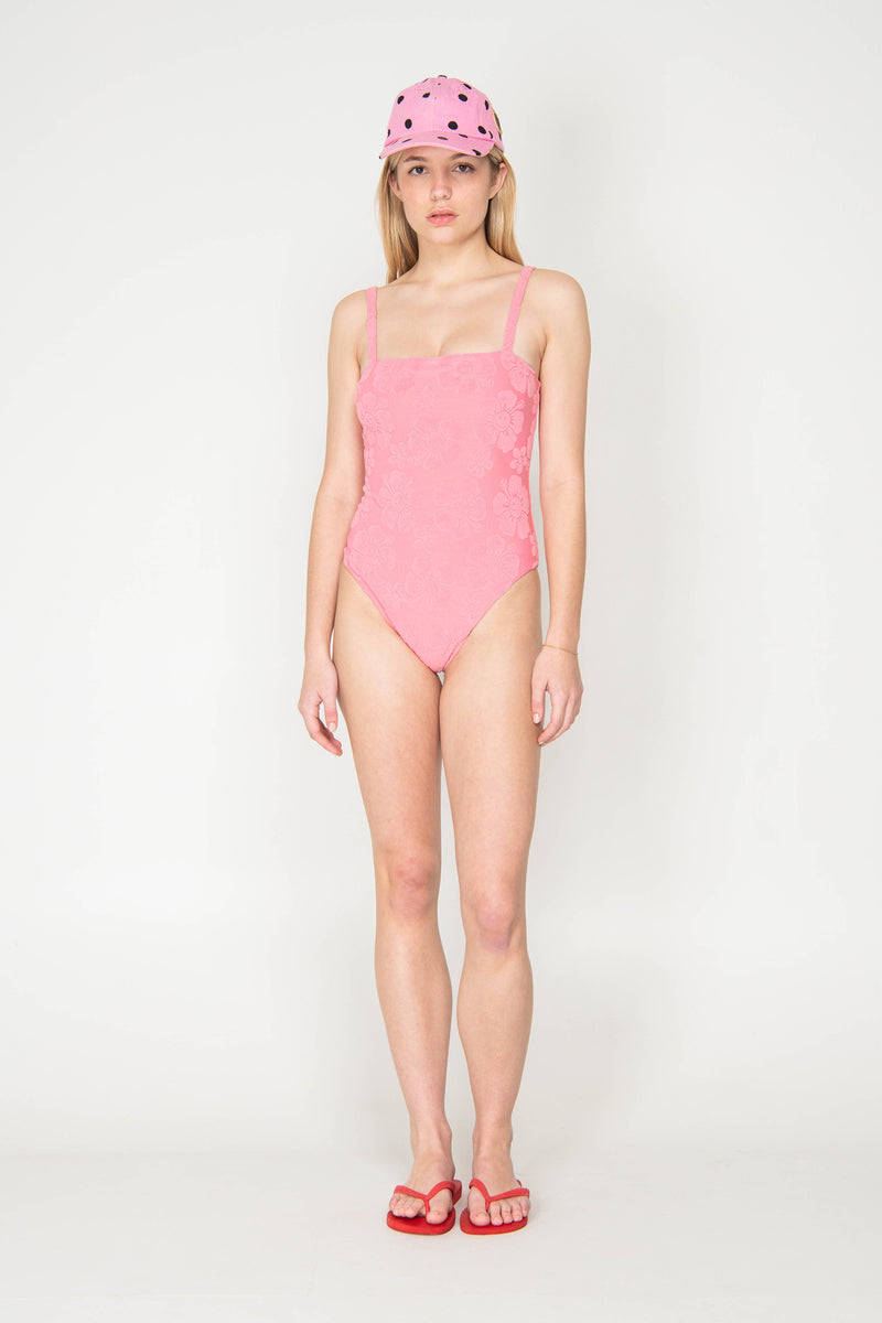 Woman wearing a pink swimsuit and cap on a white background