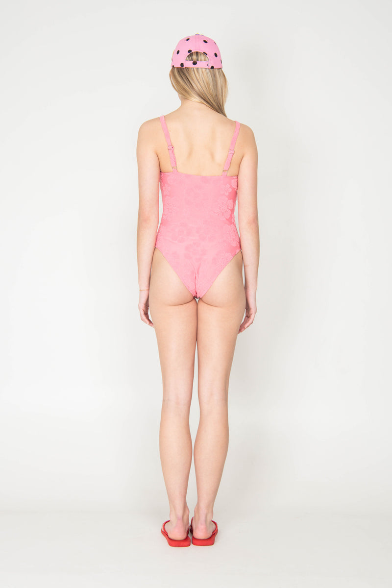 Person wearing a pink swimsuit and cap on a white background