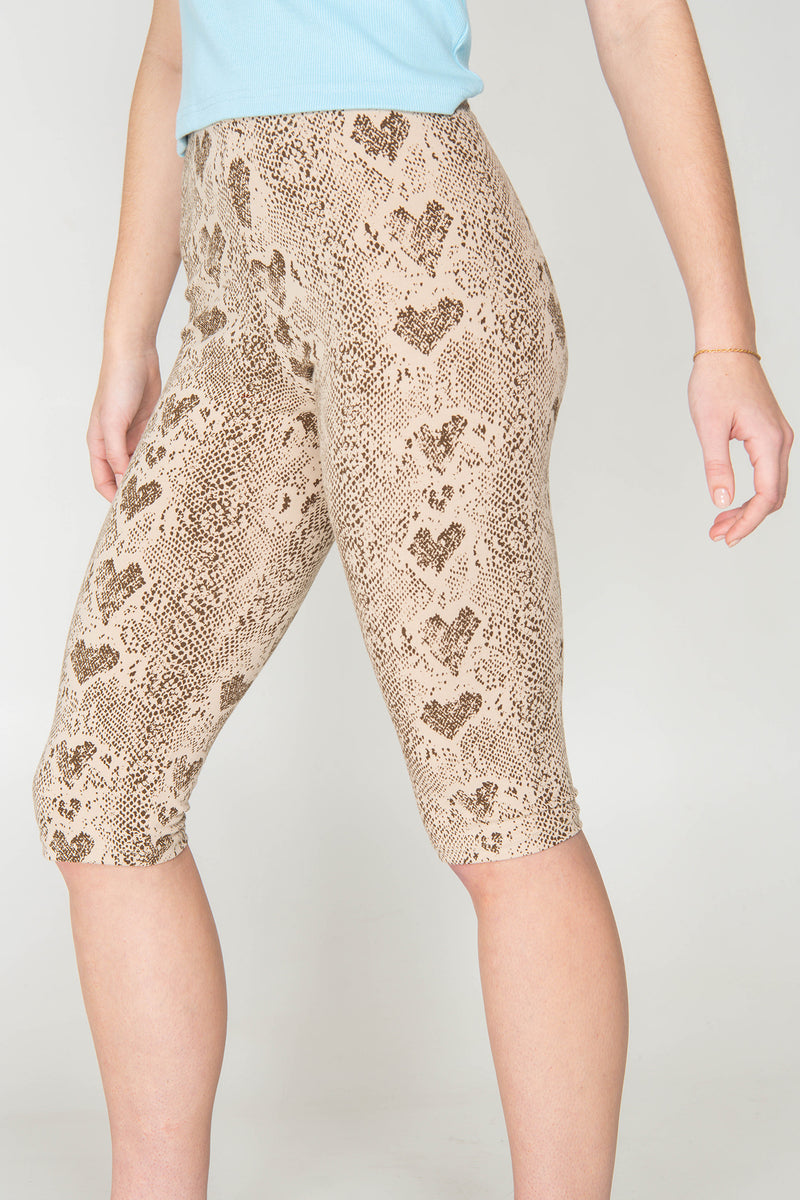 Capri leggings with snake print worn by a person on a plain background