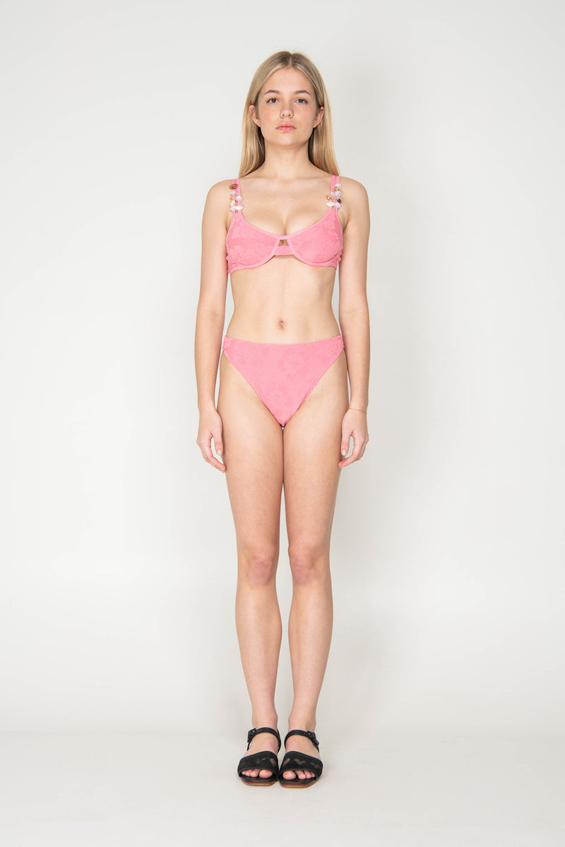 Woman wearing a pink bikini against a white background