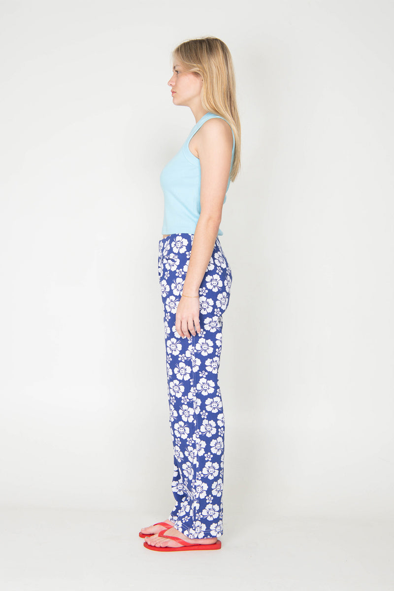 Woman wearing a light blue top and blue floral pants on a white background