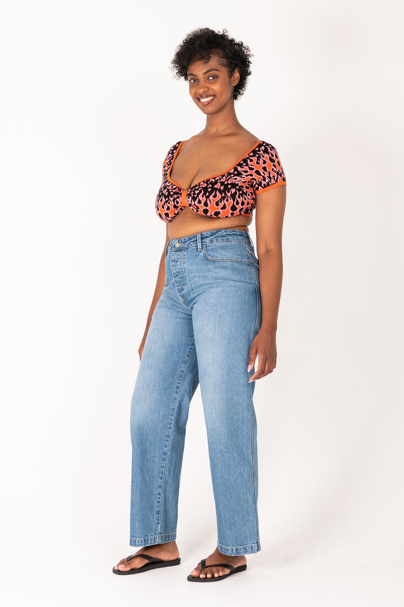 Woman wearing a flame top and blue jeans on a white background