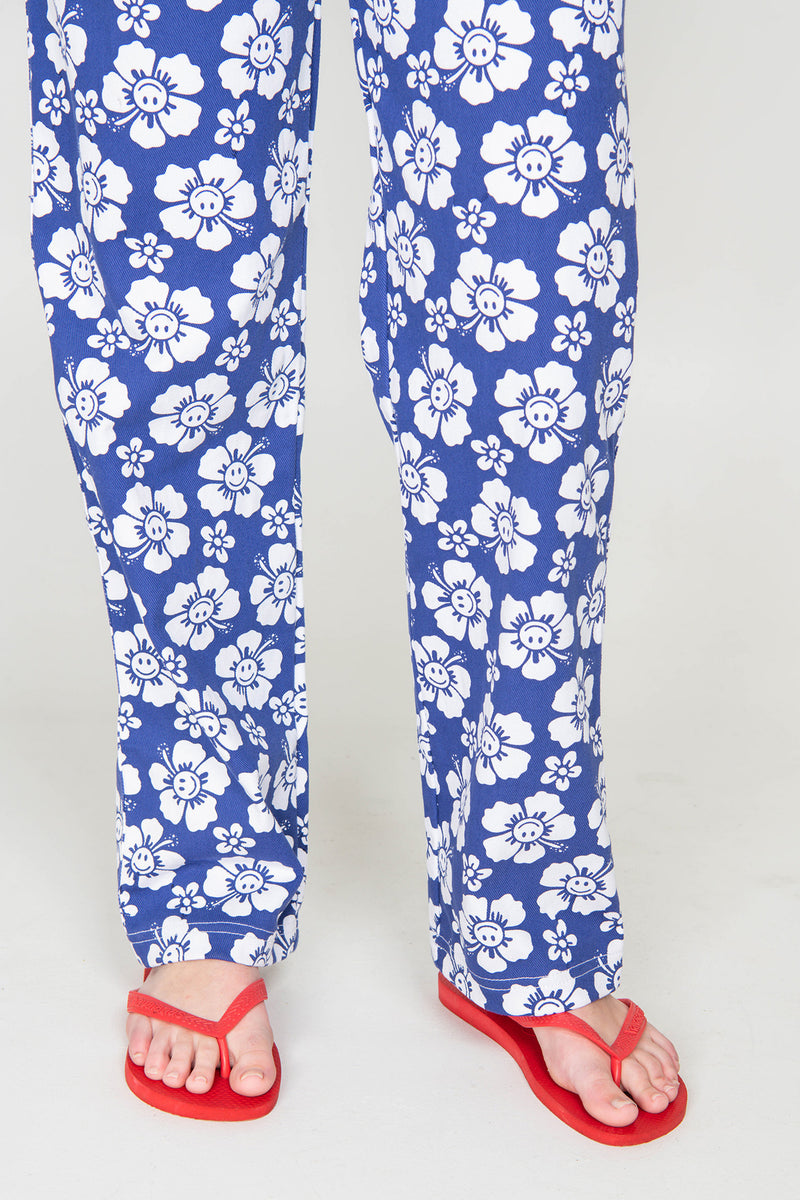 Blue pants with white floral pattern worn by a person on a white background