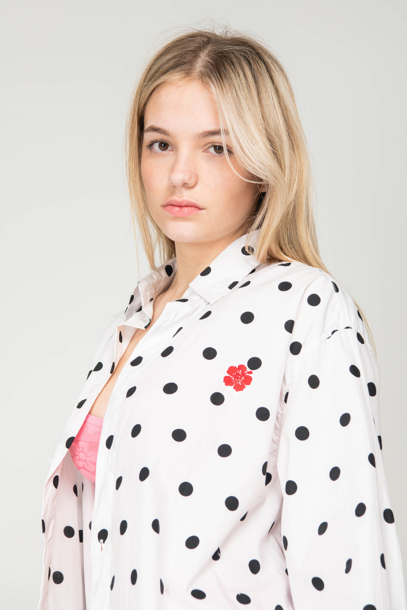 Woman wearing a polka dot kimono with a red flower design on a plain background