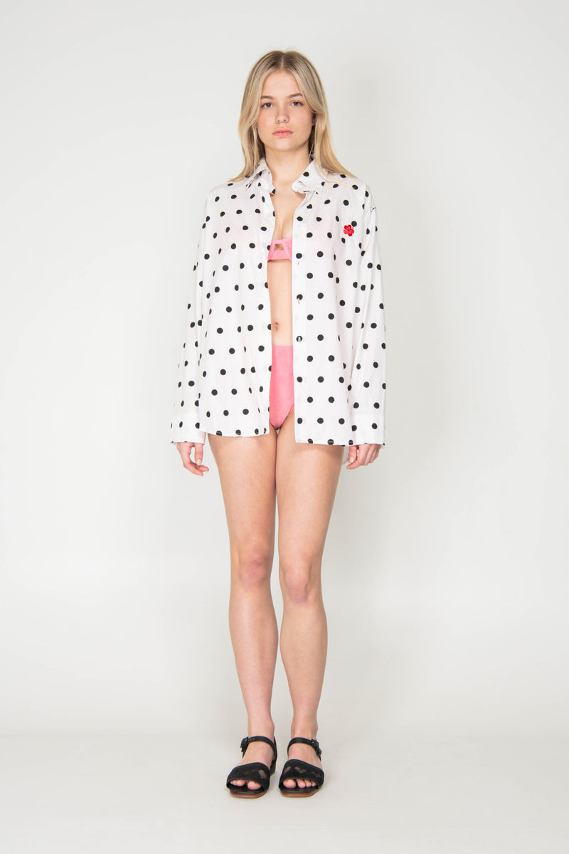Woman wearing a polka dot shirt and shorts on a white background