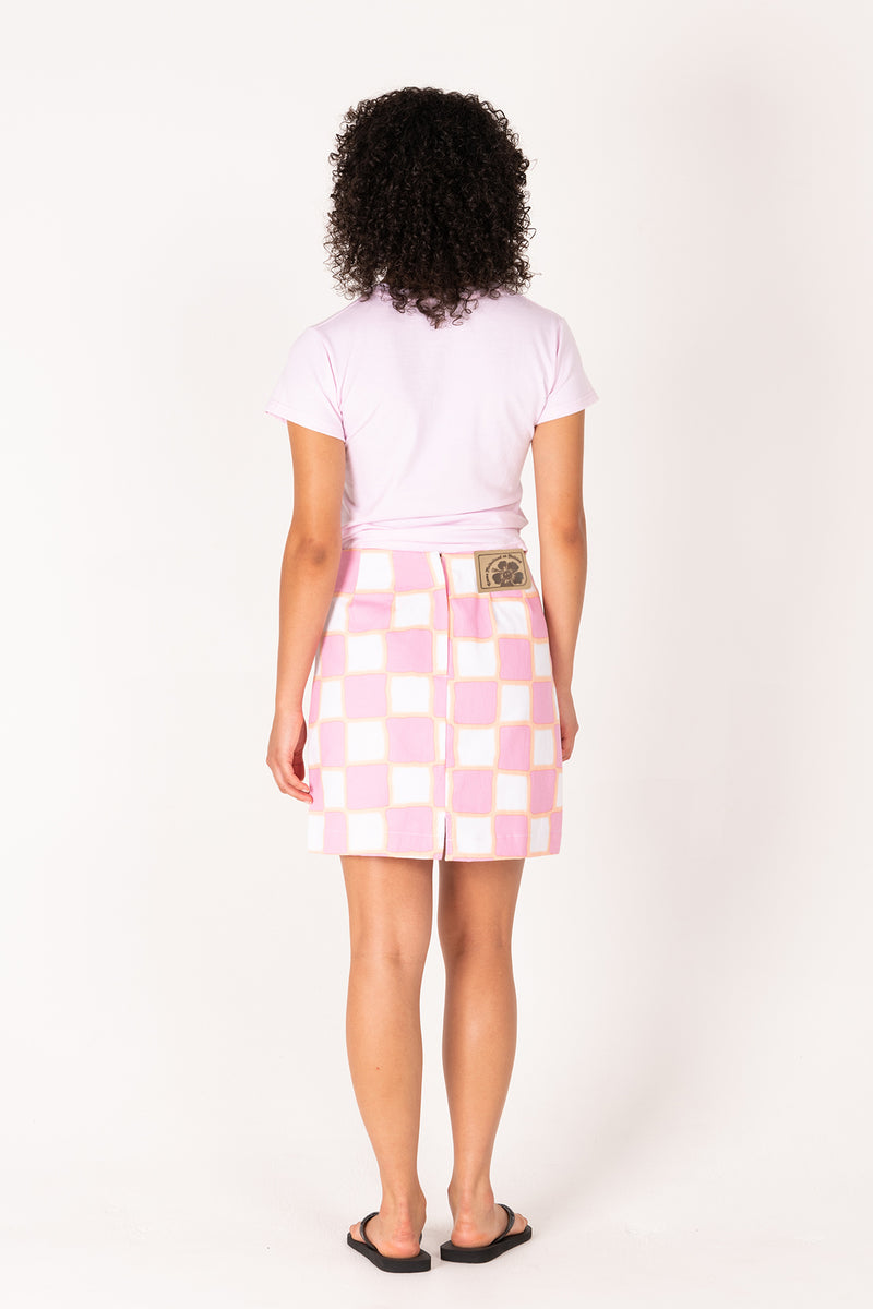 Person wearing a white t-shirt and pink checkered skirt on a white background