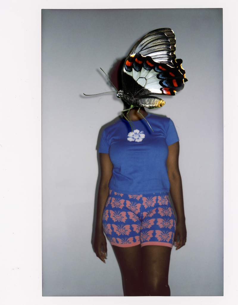 Person wearing a blue outfit with butterfly patterns, standing against a plain background