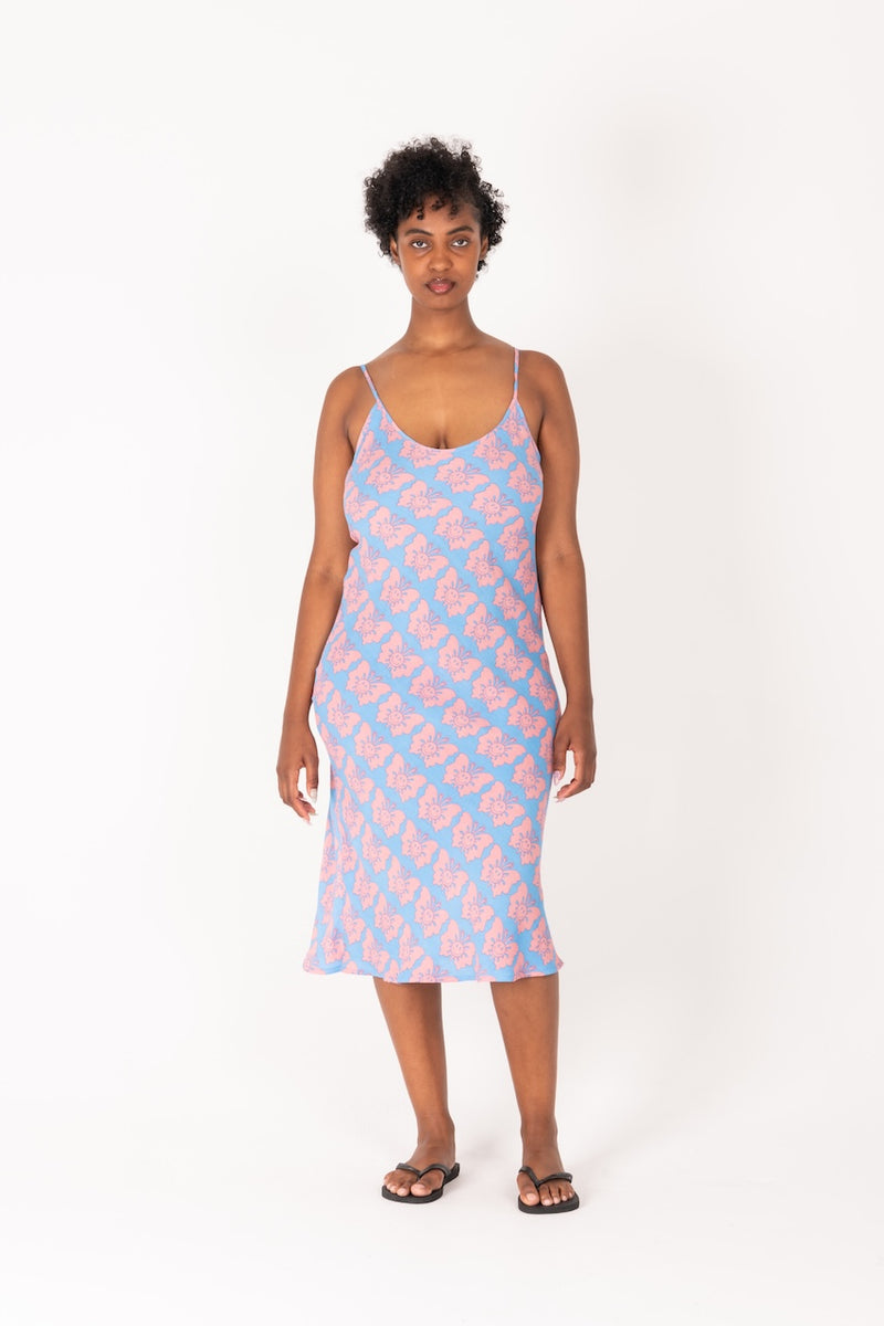 Woman wearing a pink and blue patterned slip dress on a white background