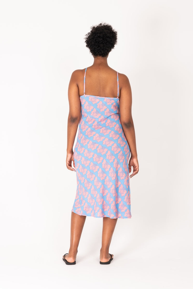 Woman wearing a light blue dress with pink patterns on a white background