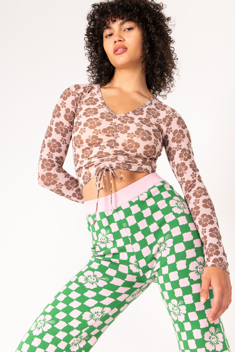 Woman wearing a floral top and green checkered pants on a white background