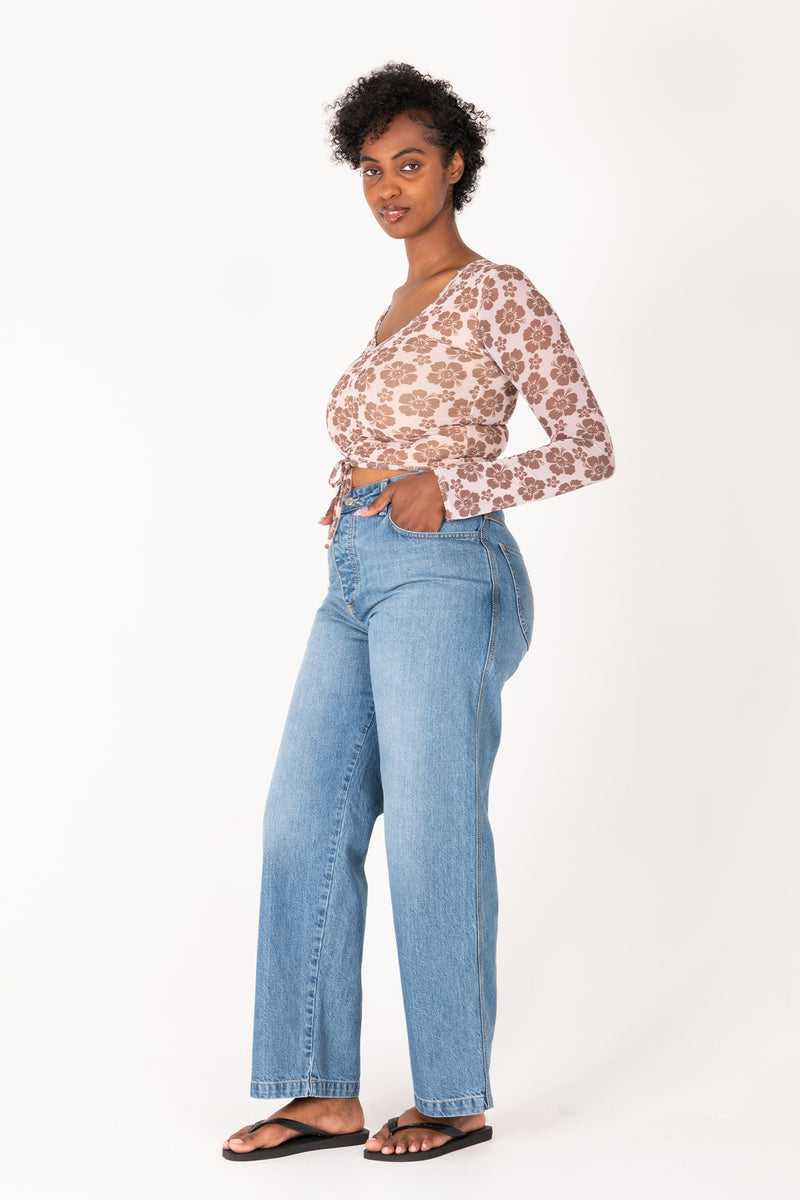 Woman wearing a floral top and blue jeans on a white background