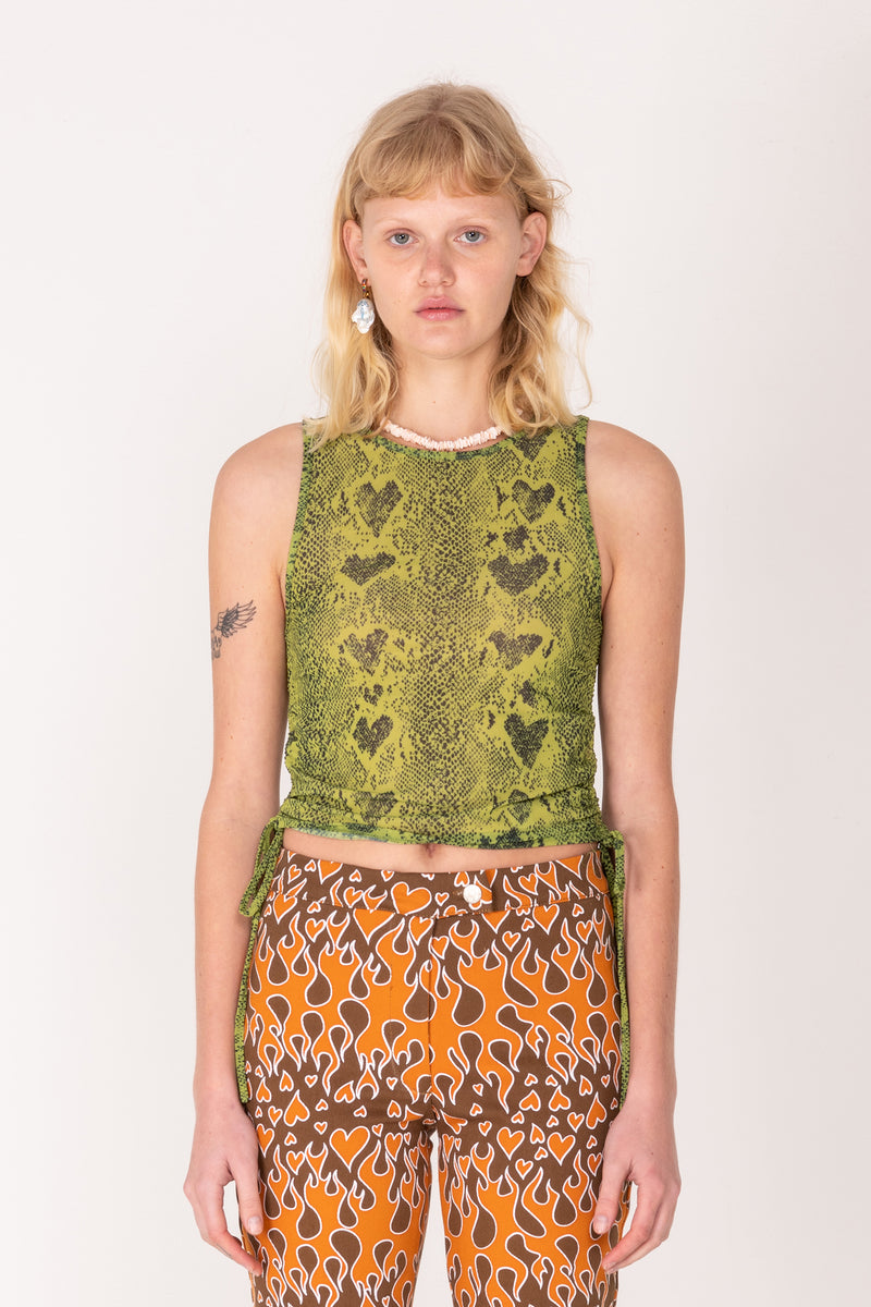 Person wearing a green patterned top and orange pants with brown hearts on a white background