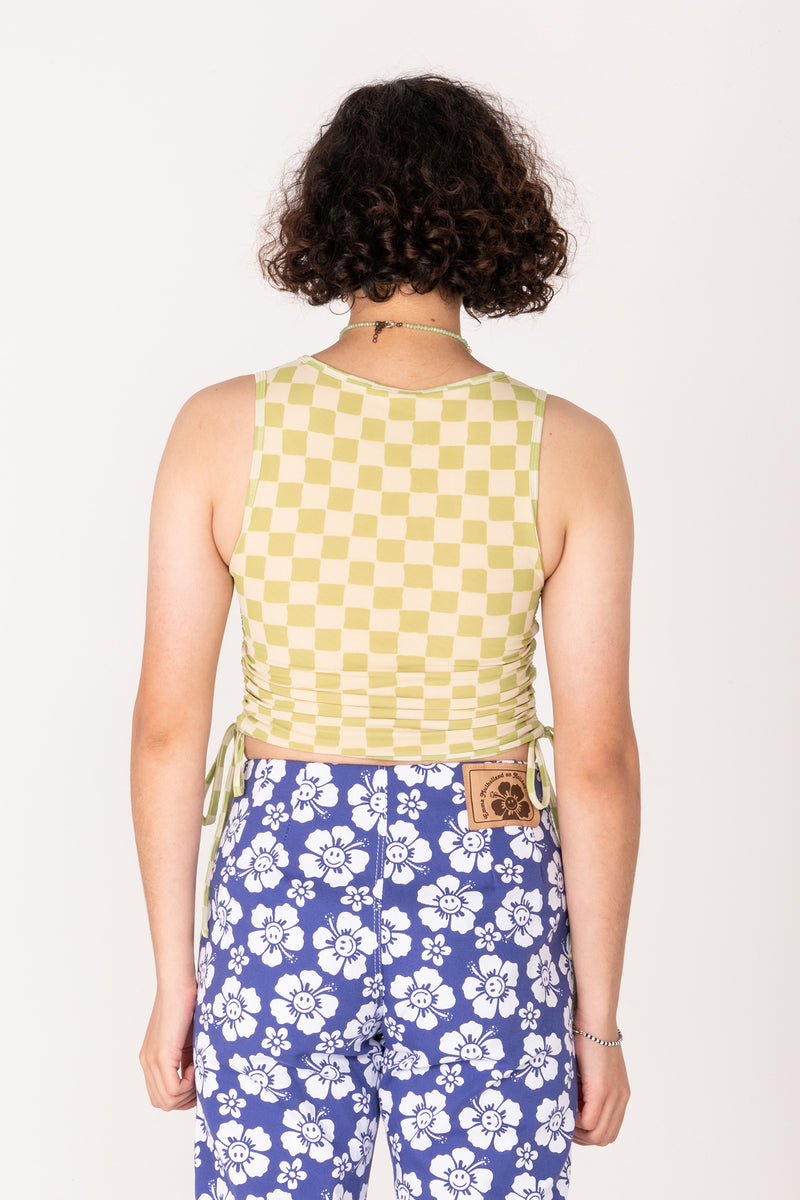 Person wearing a yellow checkered top and blue floral pants on a white background