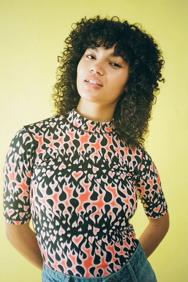 Person wearing a patterned shirt against a yellow background