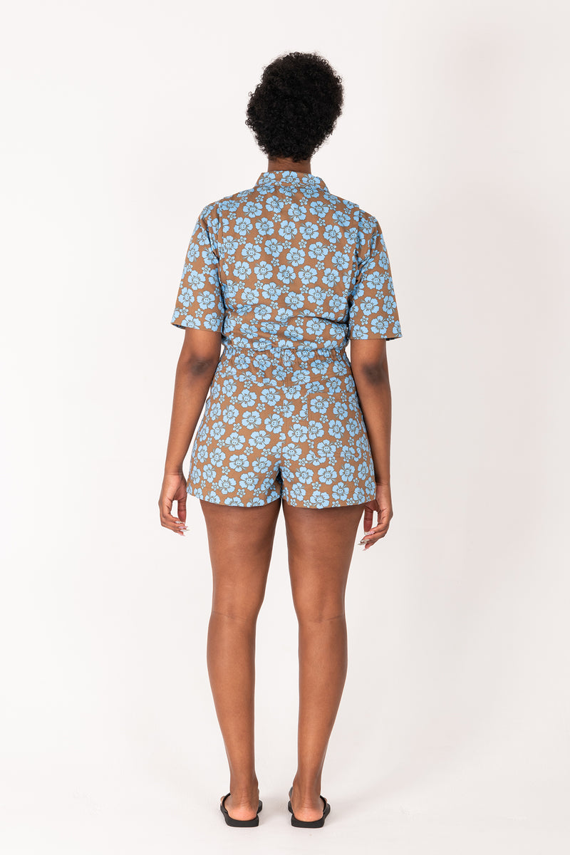 Person wearing a floral patterned romper on a white background