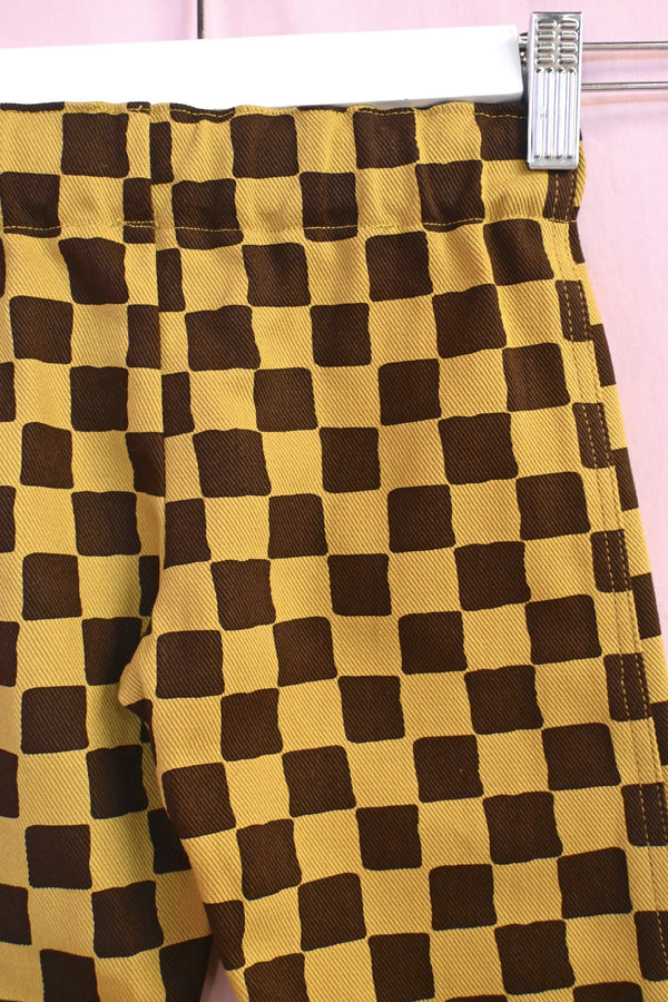 Checkered fabric with brown and yellow squares on a pink background