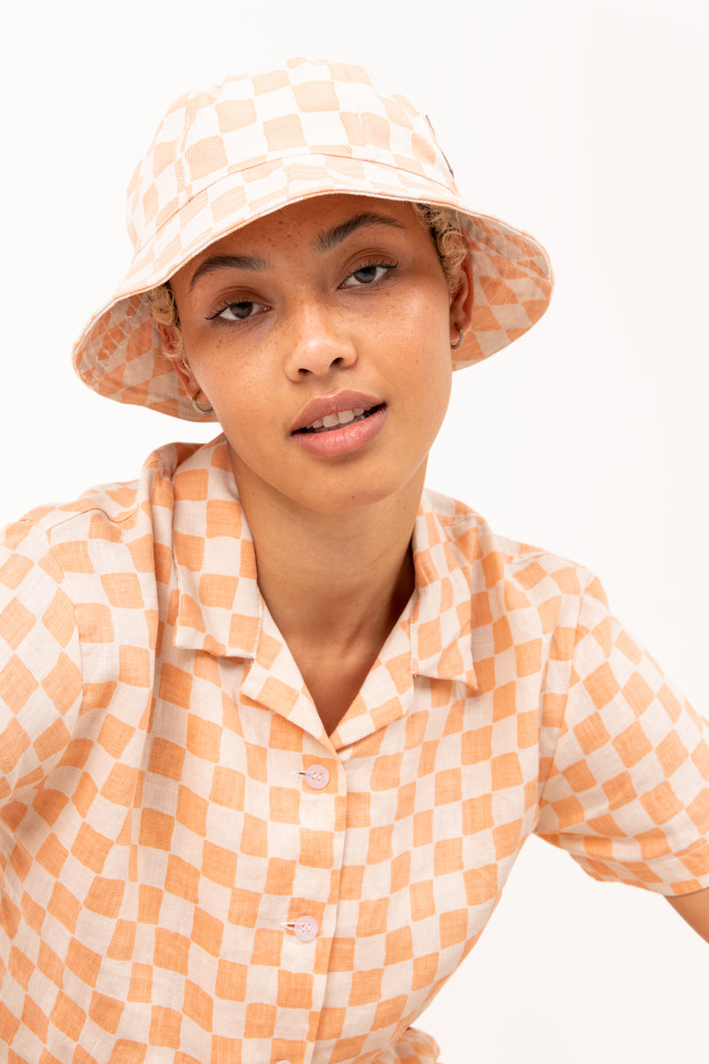 Person wearing a checkered hat and shirt on a white background