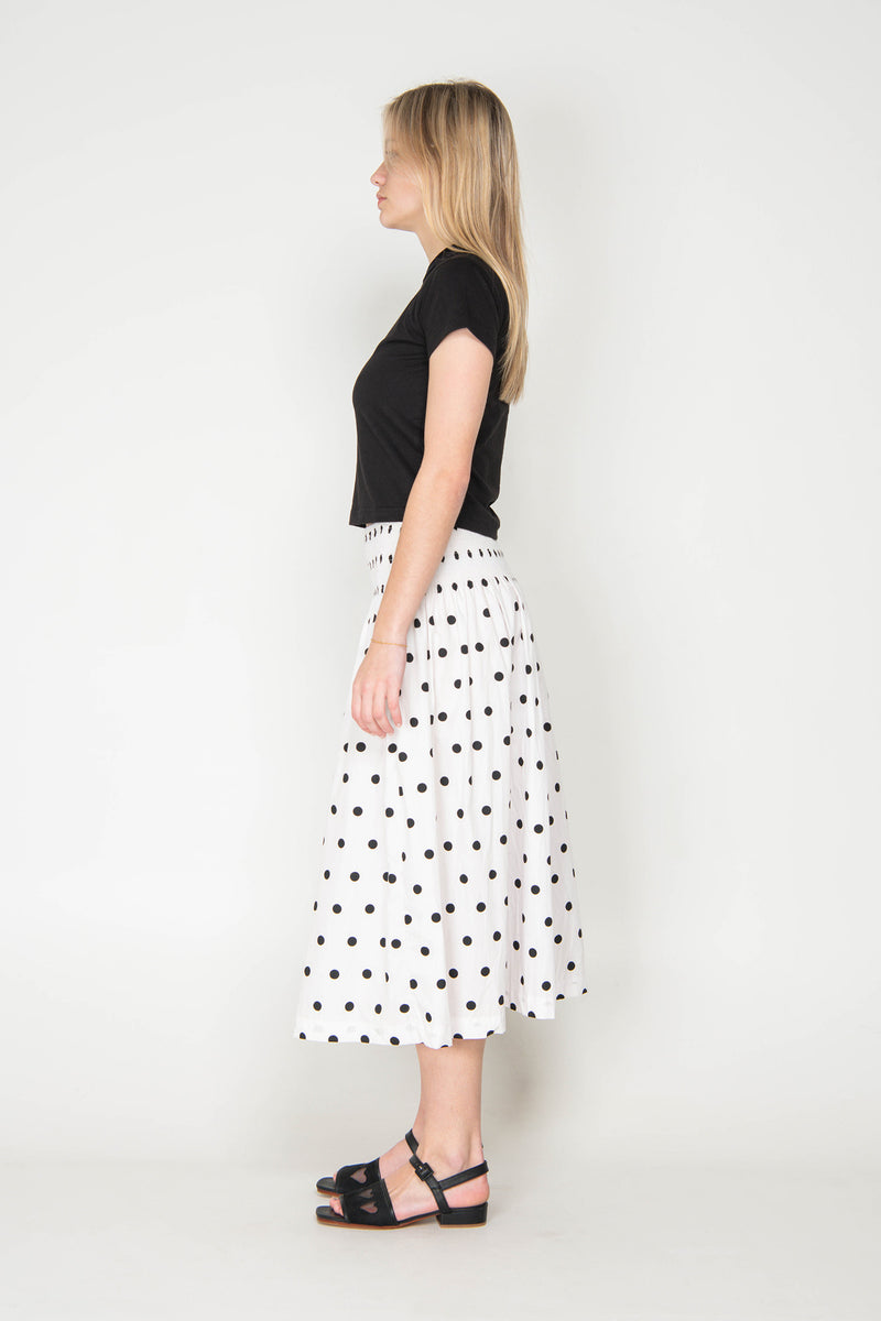 Woman wearing a black top and polka dot skirt on a white background