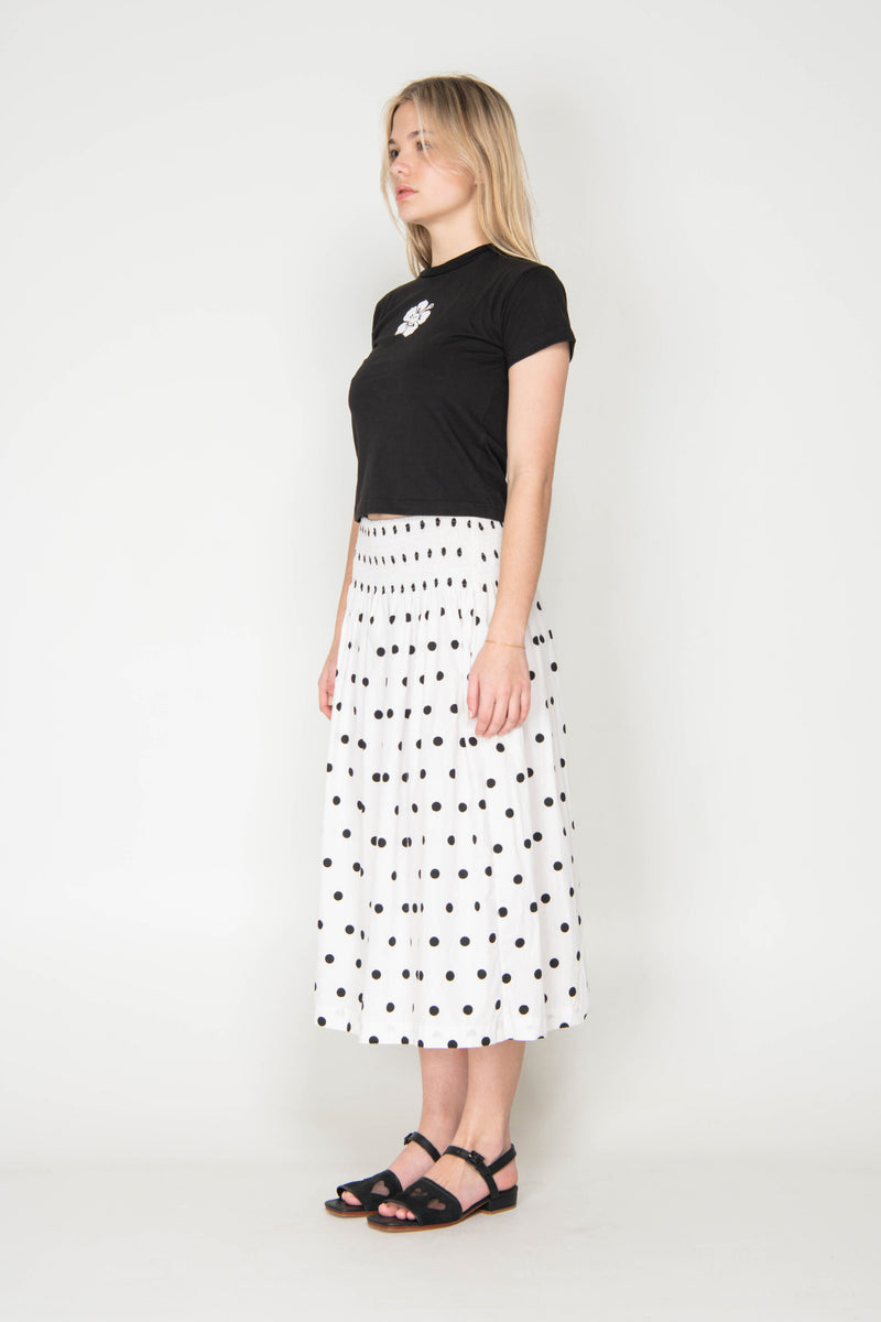 Woman wearing a black top and white polka dot skirt on a white background