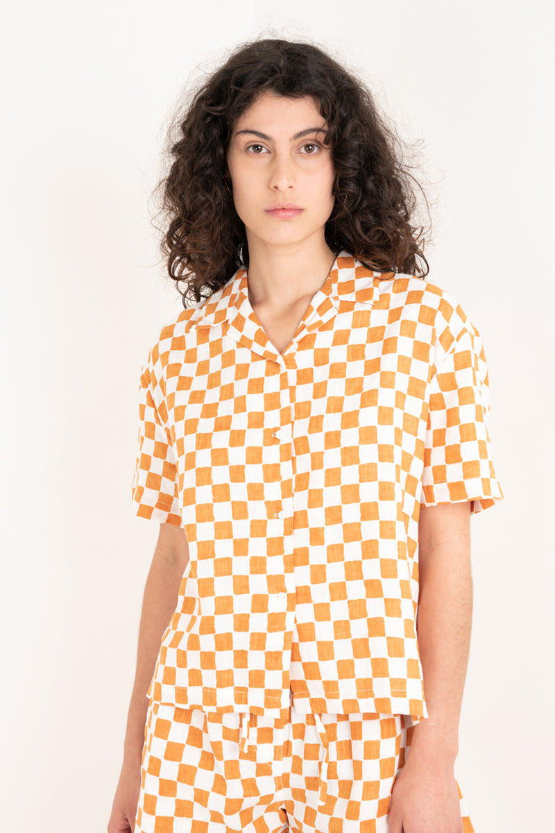 Woman wearing a yellow and white checkered shirt against a plain background
