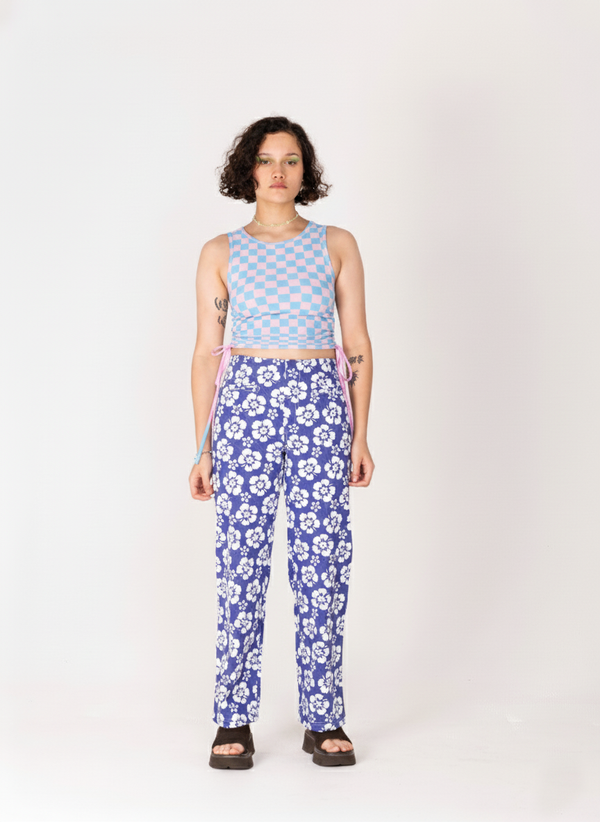 Person wearing a blue checkered top and floral pants on a white background