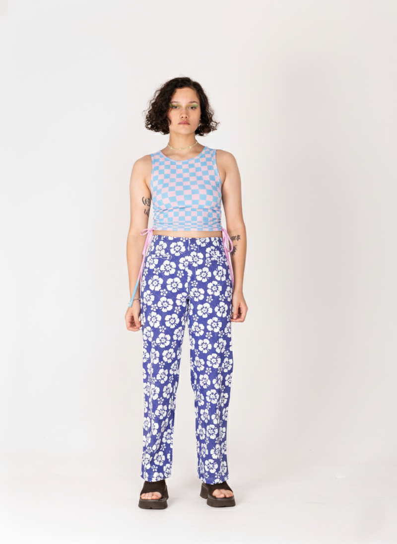 Person wearing a blue checkered top and floral pants on a white background