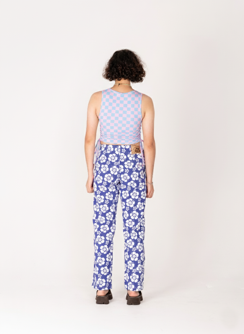 Person wearing a sleeveless checkered top and blue floral pants on a white background