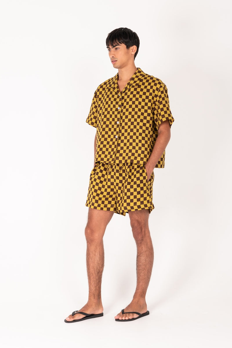 Man wearing a yellow and black checkered outfit on a white background