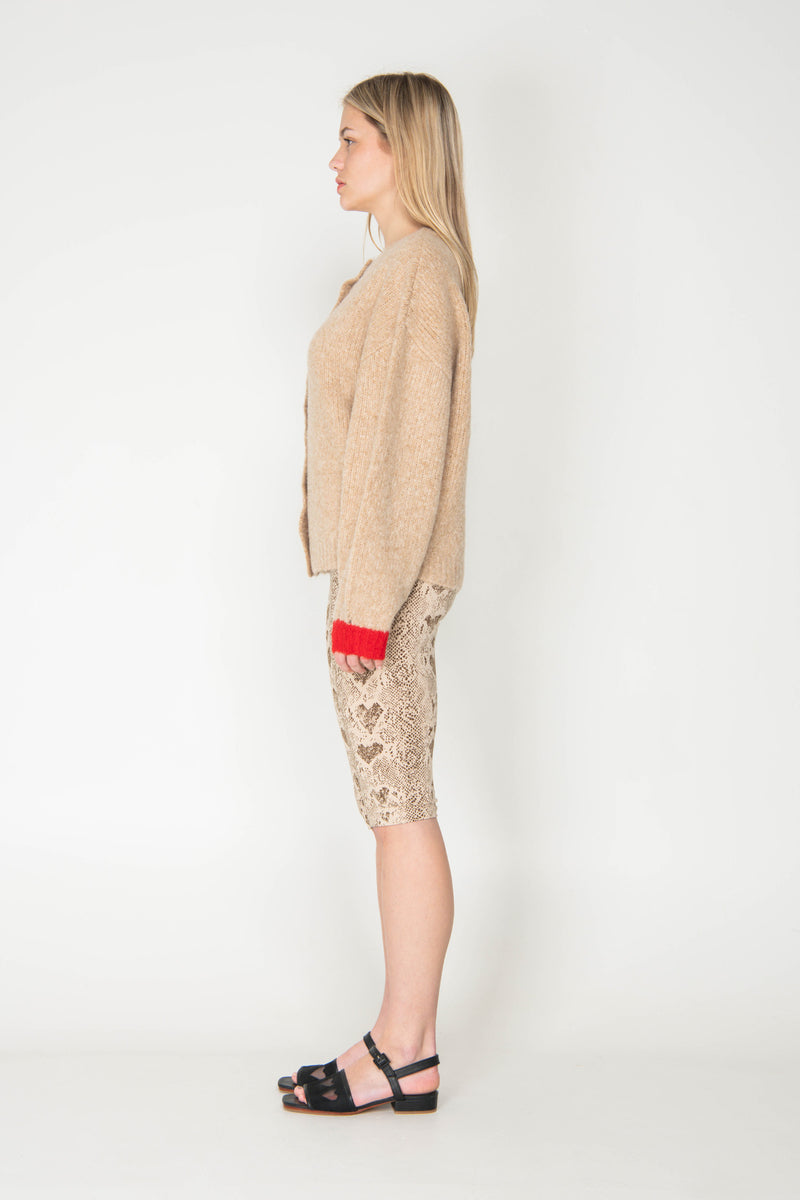 Woman wearing a beige cardigan and patterned skirt on a white background