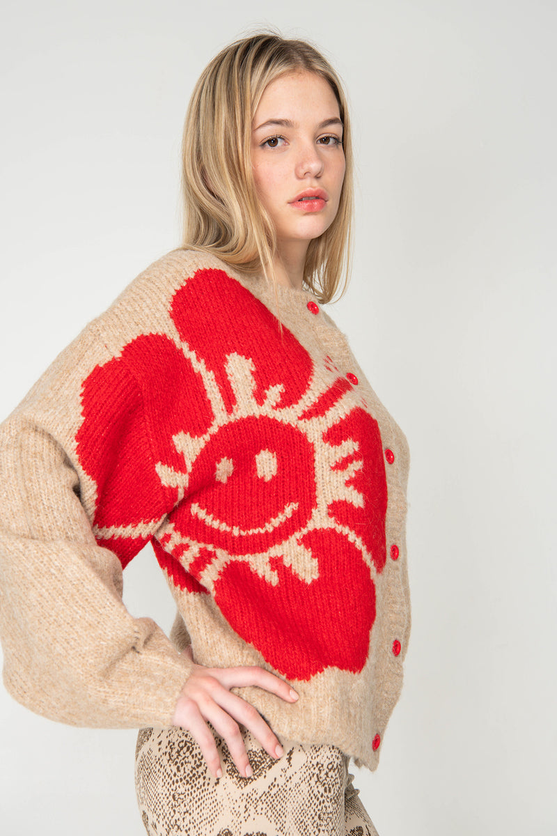 Woman wearing a beige sweater with a large red sun design on a white background