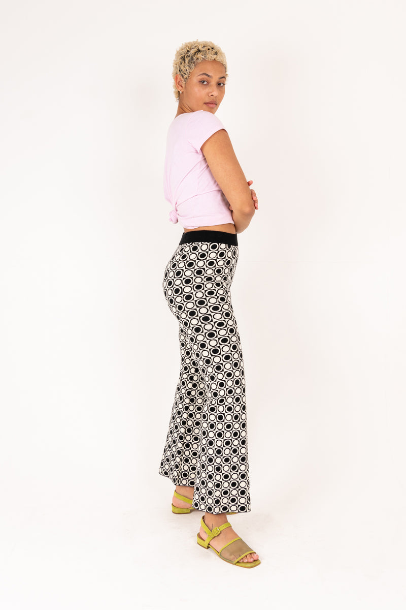 Woman wearing a pink top and patterned pants on a white background