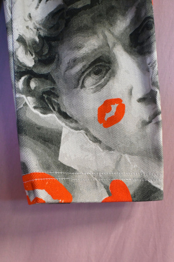 Fabric with classical sculpture design and orange lip prints on a purple background