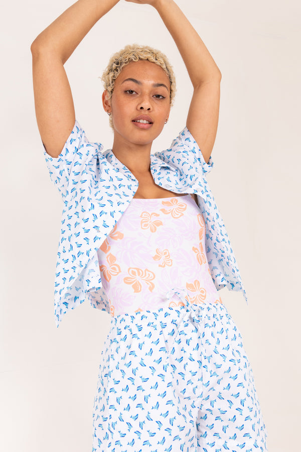 Woman wearing a floral dress with a blue patterned shawl on a plain background