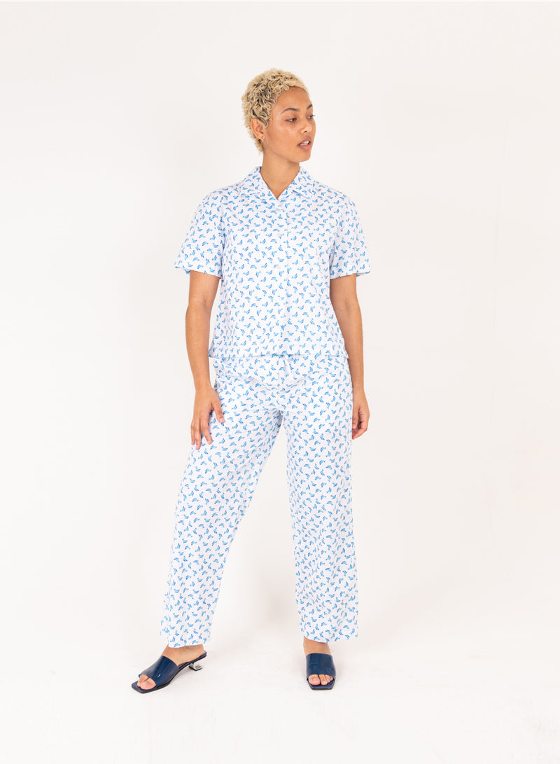 Person wearing a blue patterned pajama set on a white background