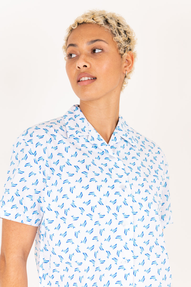 Woman wearing a white shirt with blue pattern on a plain background