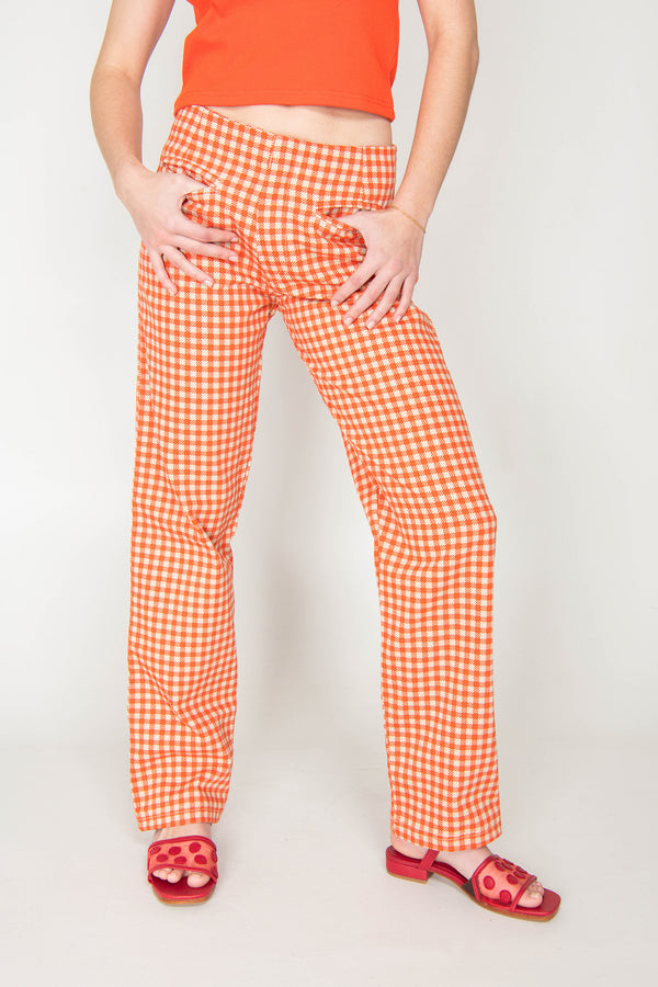 Person wearing orange checkered pants and red sandals on a white background
