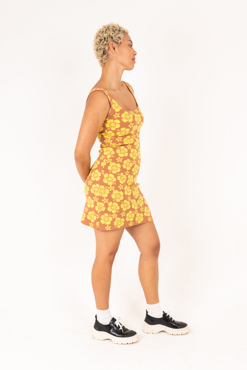 Person wearing a yellow floral dress on a white background