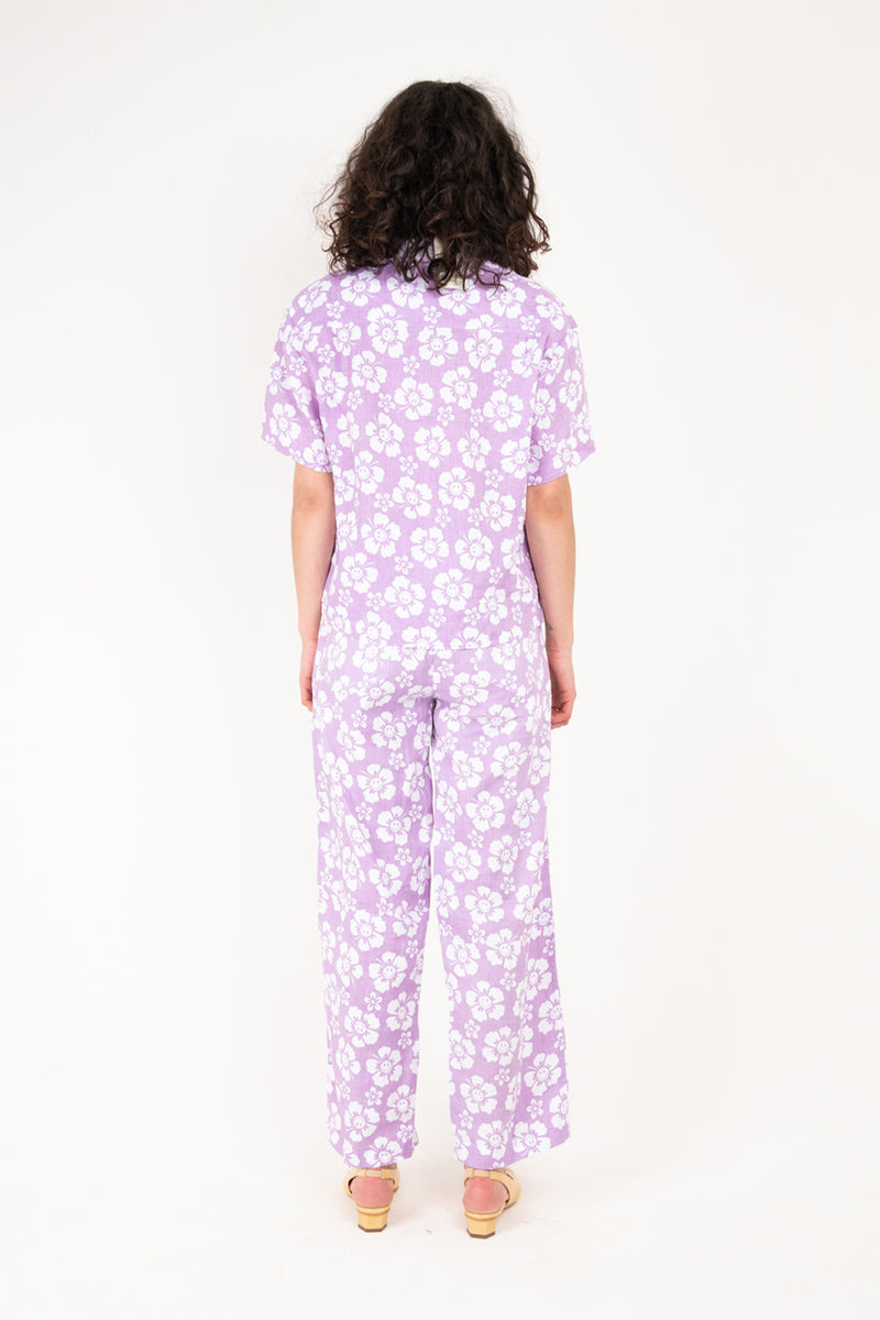 Person wearing a purple floral pajama set on a white background