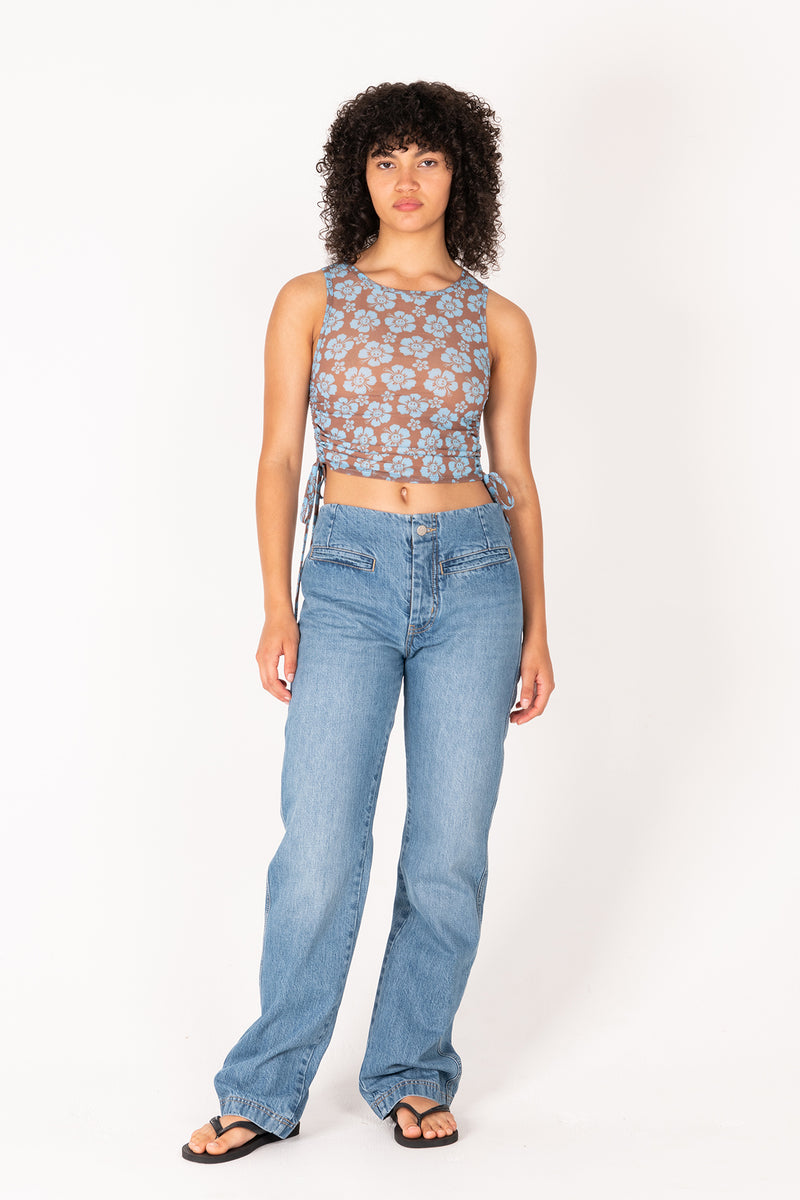 Woman wearing a patterned top and blue jeans on a white background
