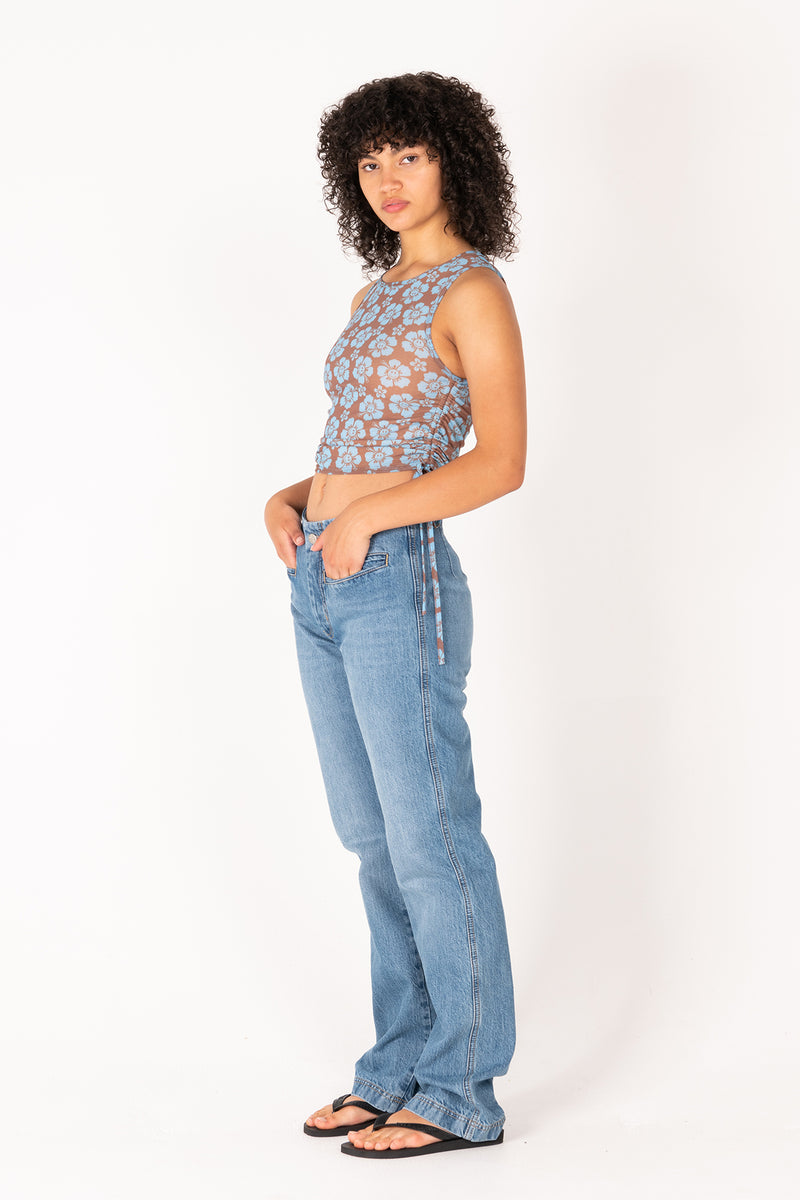 Woman wearing a patterned top and blue jeans on a white background