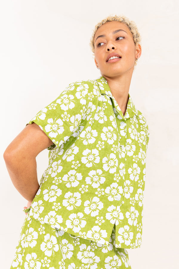 Person wearing a green and white floral shirt against a white background