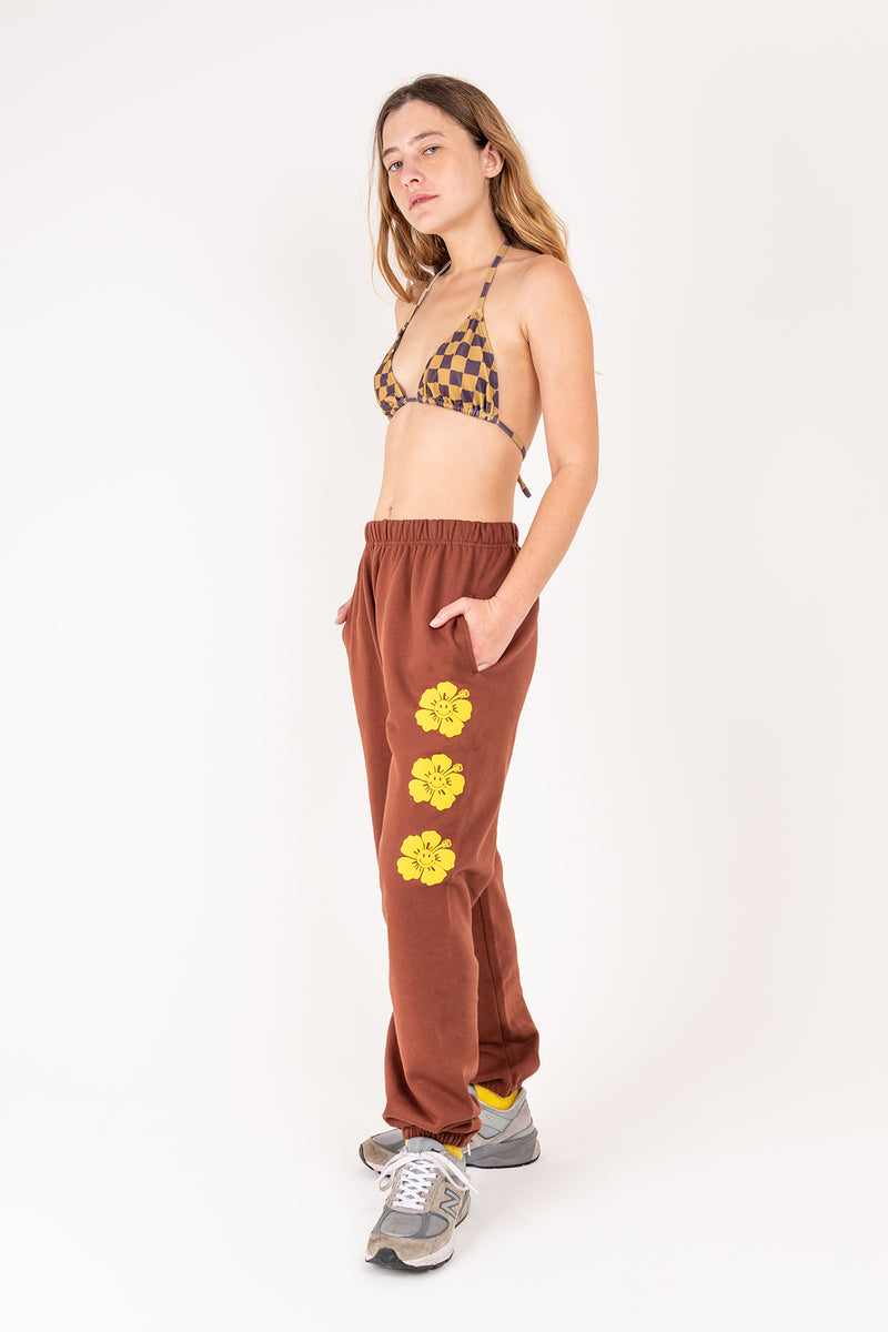 Woman wearing a patterned top and brown pants with floral designs on a white background