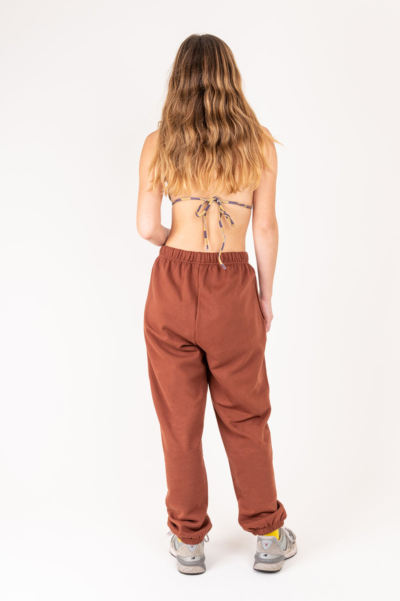 Person wearing rust-colored pants on a white background