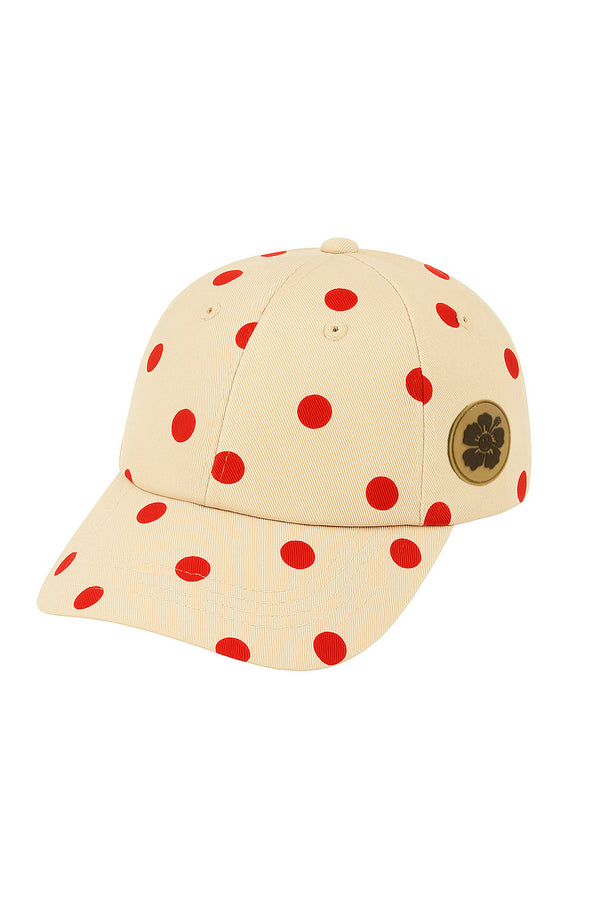 Cream cap with red polka dots and a gold logo on a white background
