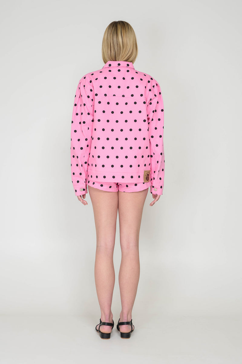Person wearing a pink polka dot shirt and shorts on a white background