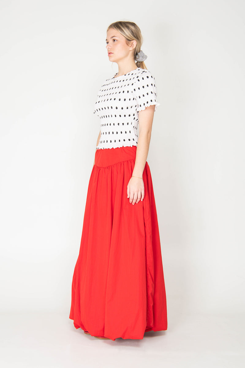 Woman wearing a black and white patterned top with a red skirt on a white background