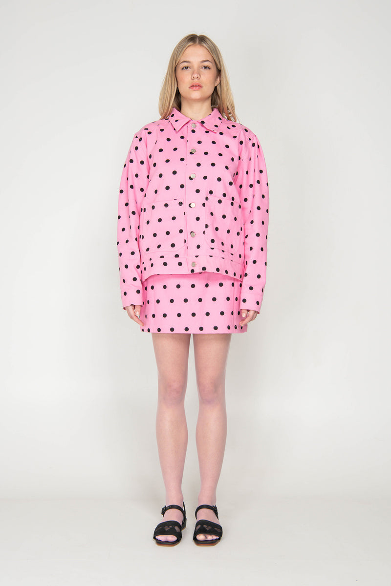 Person wearing a pink polka dot outfit on a white background