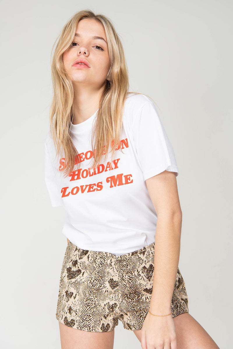Woman wearing a white t-shirt with red text and patterned shorts on a plain background