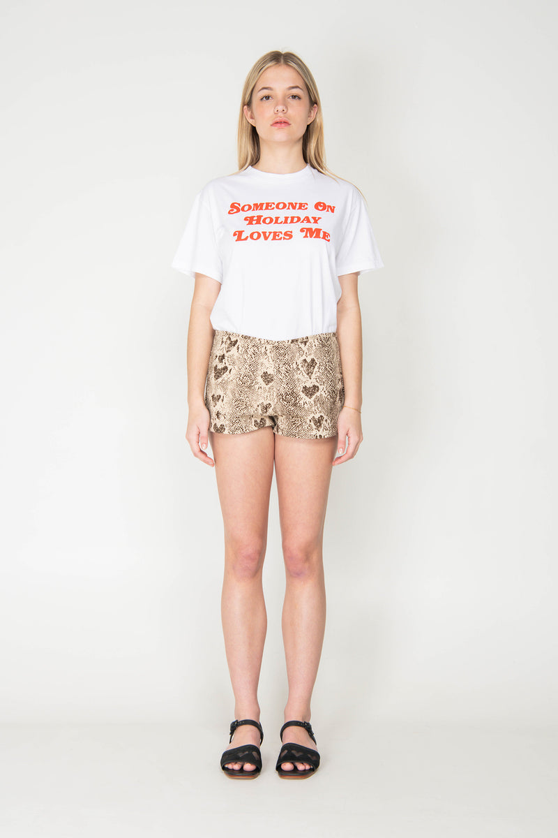 Woman wearing a white t-shirt with text and patterned shorts on a white background
