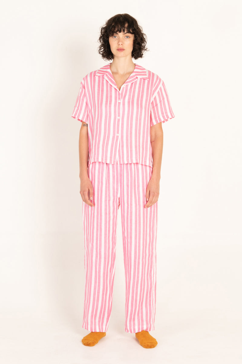 Person wearing a pink and white striped pajama set on a white background